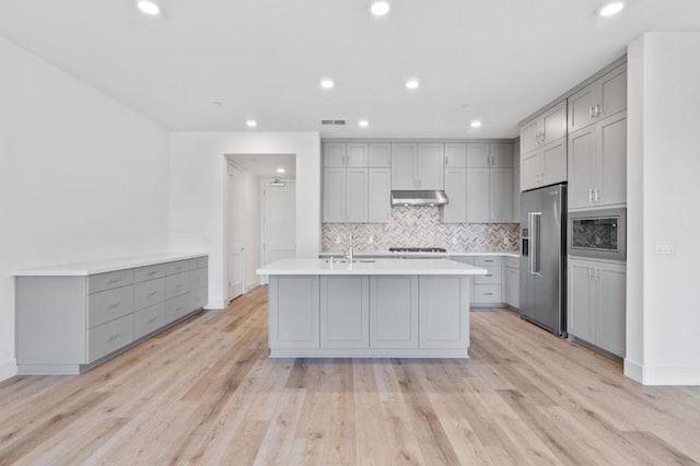 kitchen with gray cabinetry, light hardwood / wood-style floors, a center island with sink, and high end fridge