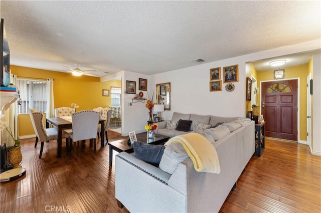 living room with a textured ceiling, hardwood / wood-style flooring, and ceiling fan