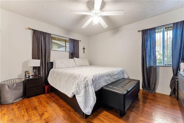 bedroom with a textured ceiling, ceiling fan, and dark hardwood / wood-style floors