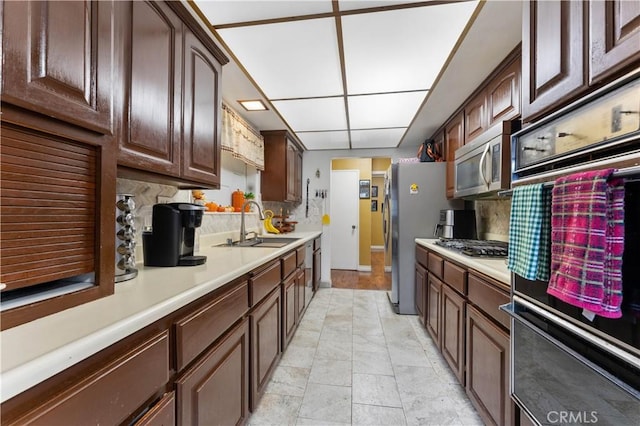 kitchen featuring decorative backsplash, dark brown cabinets, stainless steel appliances, and sink