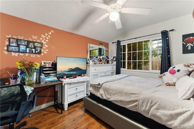 bedroom with a textured ceiling, ceiling fan, hardwood / wood-style floors, and vaulted ceiling