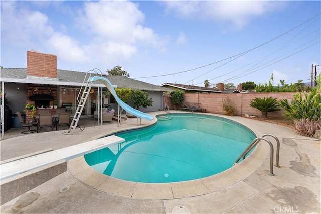 view of pool with a diving board, a patio area, and a water slide