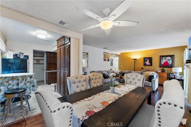 dining area with ceiling fan, wood-type flooring, and a textured ceiling