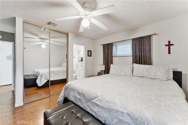 bedroom with connected bathroom, ceiling fan, hardwood / wood-style floors, a textured ceiling, and a closet