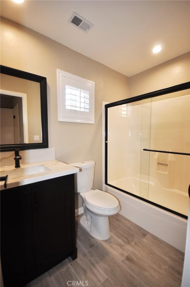 full bathroom featuring vanity, combined bath / shower with glass door, and toilet