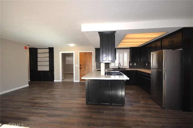 kitchen featuring sink, appliances with stainless steel finishes, tasteful backsplash, dark hardwood / wood-style flooring, and kitchen peninsula