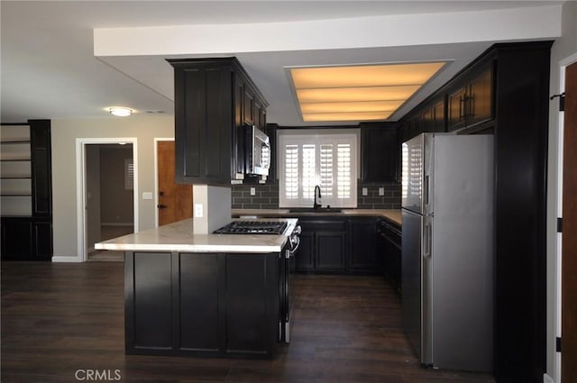 kitchen with sink, appliances with stainless steel finishes, dark hardwood / wood-style flooring, a raised ceiling, and decorative backsplash