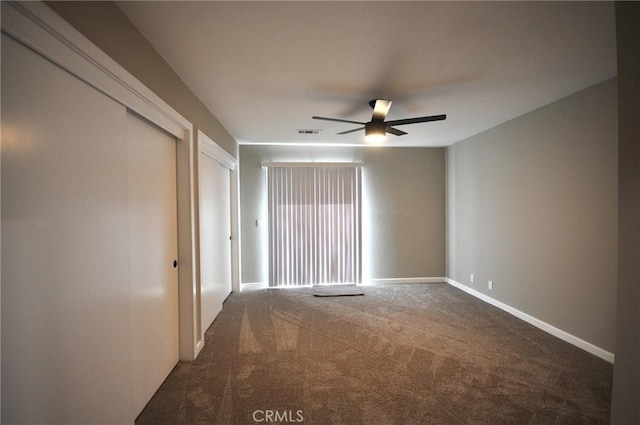 spare room featuring ceiling fan and dark colored carpet