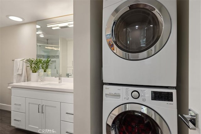 clothes washing area with dark wood-type flooring, sink, and stacked washer and dryer