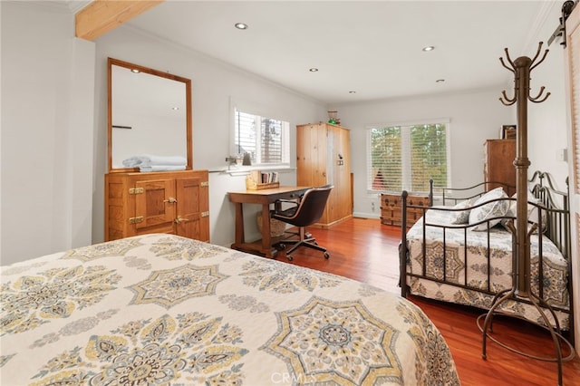 bedroom with a barn door, wood-type flooring, and ornamental molding