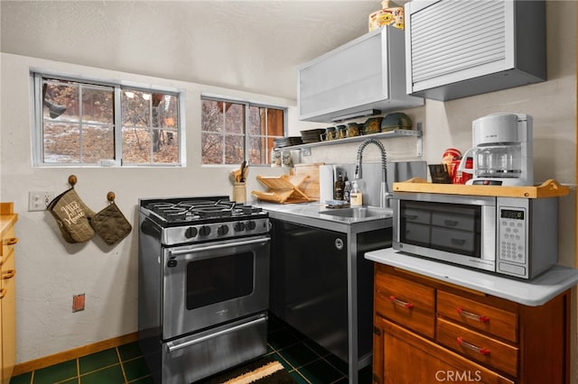 kitchen with dark tile patterned flooring, a healthy amount of sunlight, sink, and appliances with stainless steel finishes