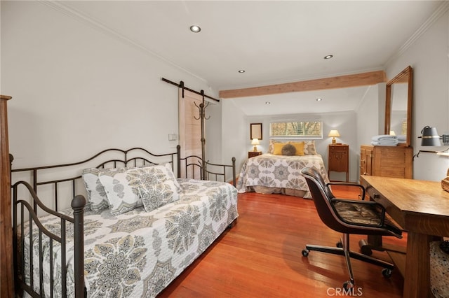 bedroom with a barn door, crown molding, and light hardwood / wood-style flooring