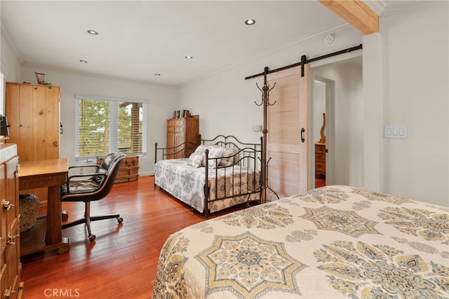 bedroom featuring hardwood / wood-style floors, a barn door, and crown molding