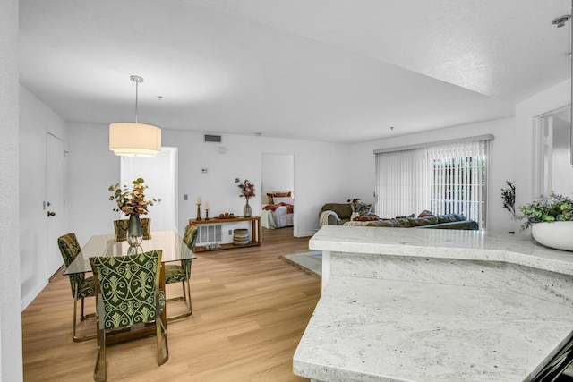 kitchen with decorative light fixtures, light stone countertops, and light wood-type flooring