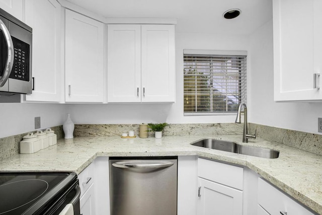 kitchen with light stone countertops, sink, white cabinets, and stainless steel appliances