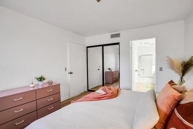 bedroom featuring connected bathroom, a closet, and light wood-type flooring