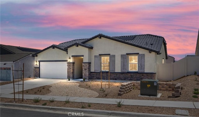 view of front of house with driveway, a garage, stucco siding, a tile roof, and fence