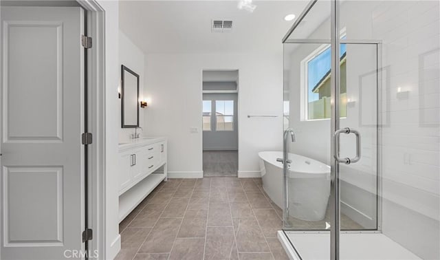 bathroom with vanity, a shower stall, a soaking tub, and baseboards