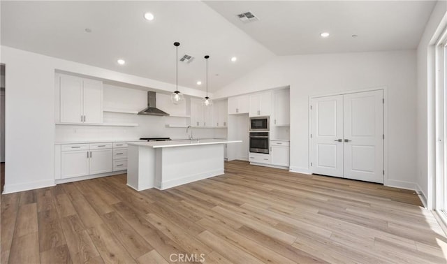 kitchen with appliances with stainless steel finishes, open shelves, white cabinetry, lofted ceiling, and wall chimney exhaust hood