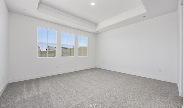 unfurnished room with crown molding, a tray ceiling, carpet flooring, baseboards, and recessed lighting