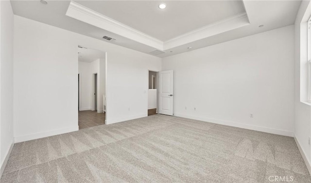 carpeted empty room with a raised ceiling, ornamental molding, baseboards, and recessed lighting