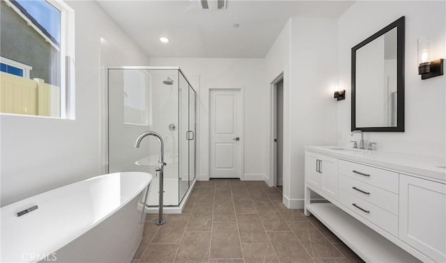 full bathroom featuring vanity, a shower stall, a freestanding bath, recessed lighting, and baseboards