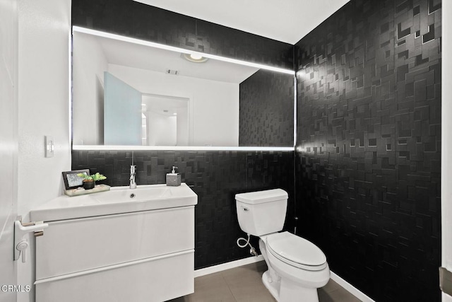 bathroom with toilet, vanity, tile patterned floors, and tile walls