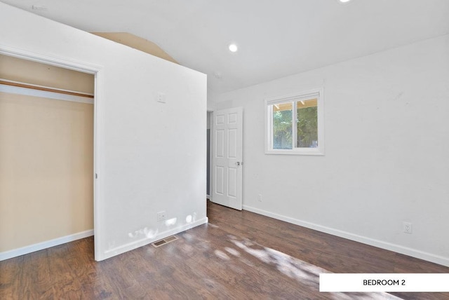 unfurnished bedroom with lofted ceiling, dark wood-type flooring, and a closet