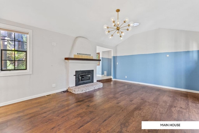 unfurnished living room with dark wood-type flooring, lofted ceiling, a fireplace, and an inviting chandelier