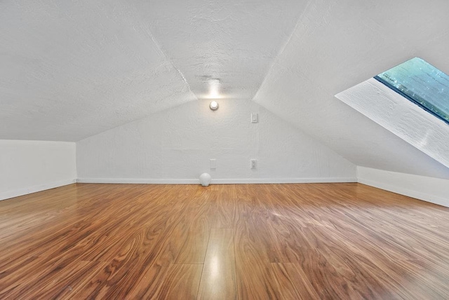 bonus room featuring hardwood / wood-style flooring, vaulted ceiling, and a textured ceiling