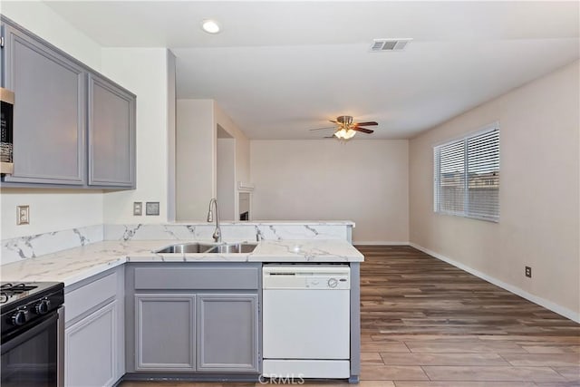 kitchen featuring gray cabinetry, dishwasher, sink, and hardwood / wood-style flooring