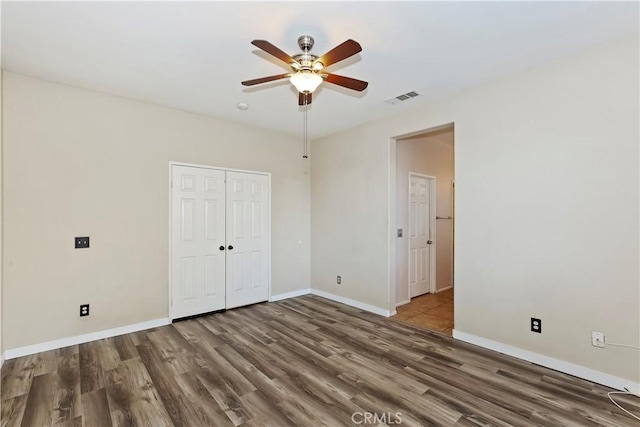 unfurnished bedroom with dark hardwood / wood-style floors, ceiling fan, and a closet