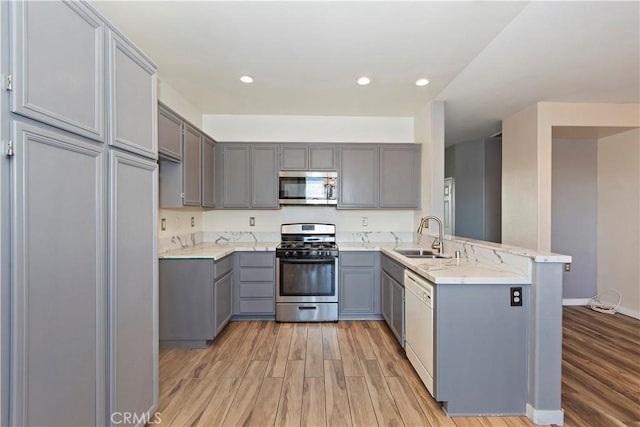 kitchen with kitchen peninsula, stainless steel appliances, gray cabinets, and sink