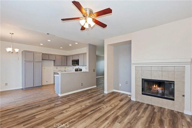 kitchen featuring a tile fireplace, pendant lighting, gray cabinetry, and hardwood / wood-style floors