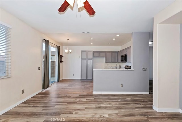 kitchen featuring hanging light fixtures, ceiling fan with notable chandelier, gray cabinets, and dark hardwood / wood-style floors