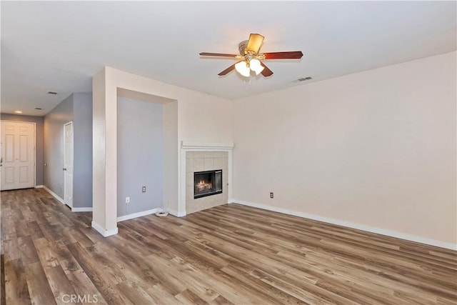 unfurnished living room with ceiling fan, a fireplace, and wood-type flooring