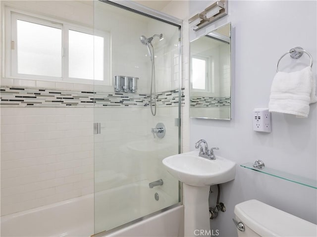 bathroom featuring combined bath / shower with glass door and toilet