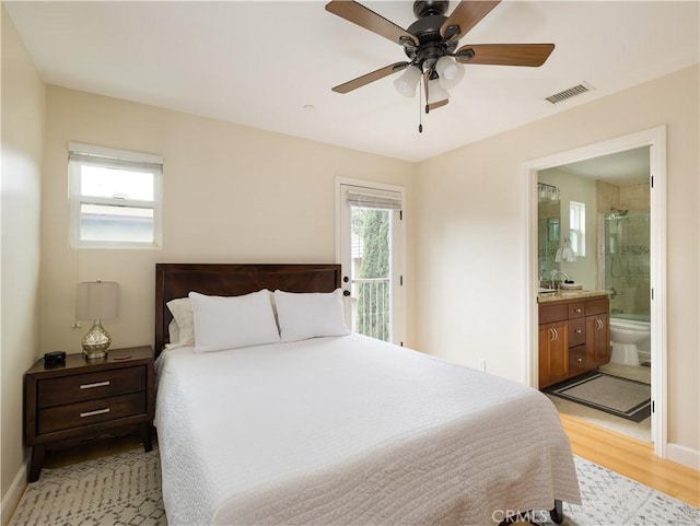 bedroom featuring multiple windows, ensuite bath, light hardwood / wood-style flooring, and access to outside