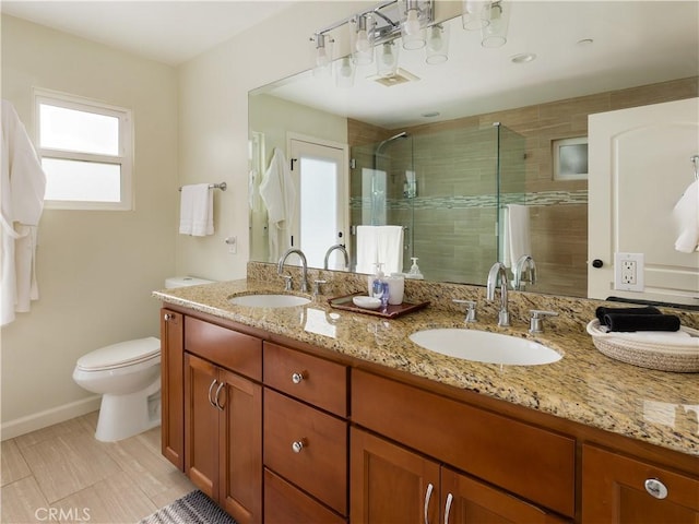 bathroom featuring a shower with door, vanity, and toilet