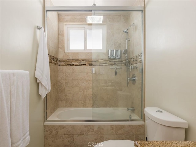 bathroom featuring toilet and combined bath / shower with glass door