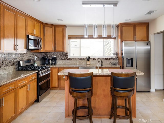 kitchen featuring an island with sink, appliances with stainless steel finishes, and a kitchen breakfast bar