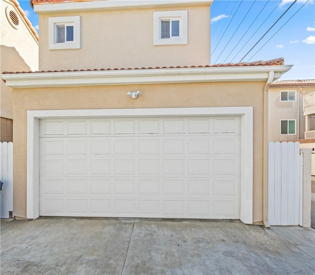 garage featuring concrete driveway and fence