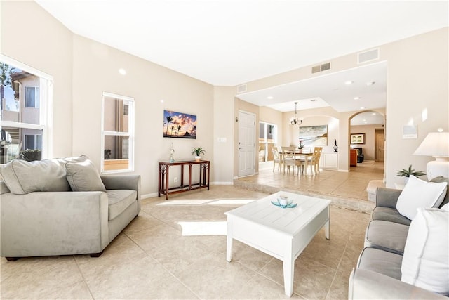 living room featuring light tile patterned floors, visible vents, and arched walkways