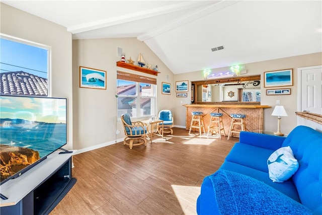 living room with vaulted ceiling with beams, baseboards, visible vents, and wood finished floors