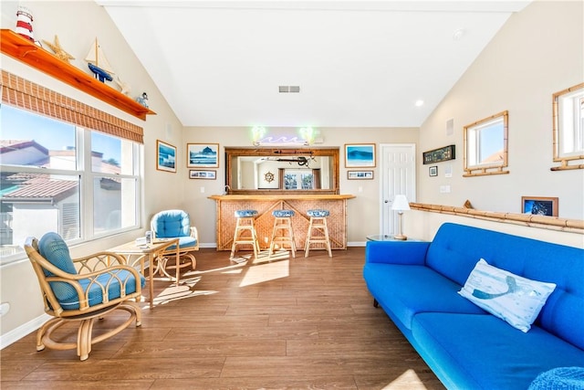 living room featuring vaulted ceiling, hardwood / wood-style flooring, and bar area