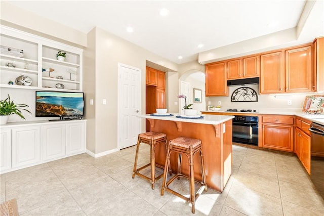 kitchen featuring light tile patterned floors, a kitchen island, black appliances, a breakfast bar, and built in shelves