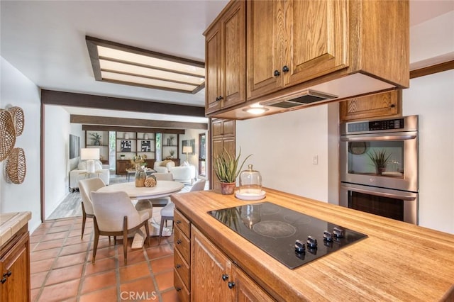 kitchen with double oven, black electric cooktop, tile patterned floors, and butcher block counters