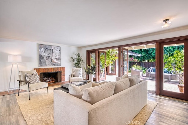 living room with a wealth of natural light, light hardwood / wood-style flooring, crown molding, and a brick fireplace