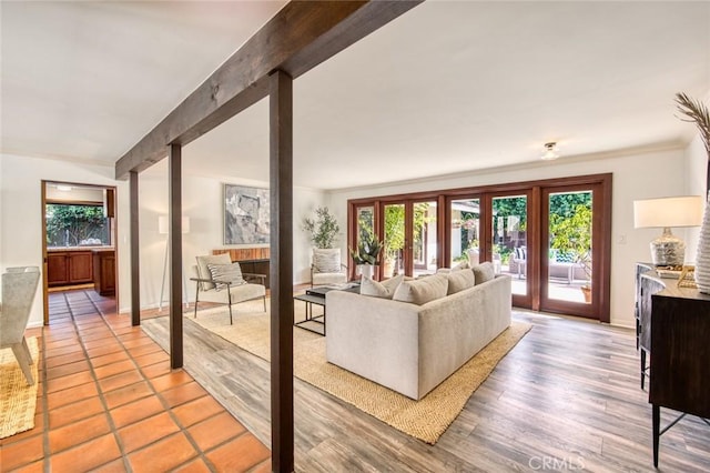 living room featuring beam ceiling, light wood-type flooring, and french doors