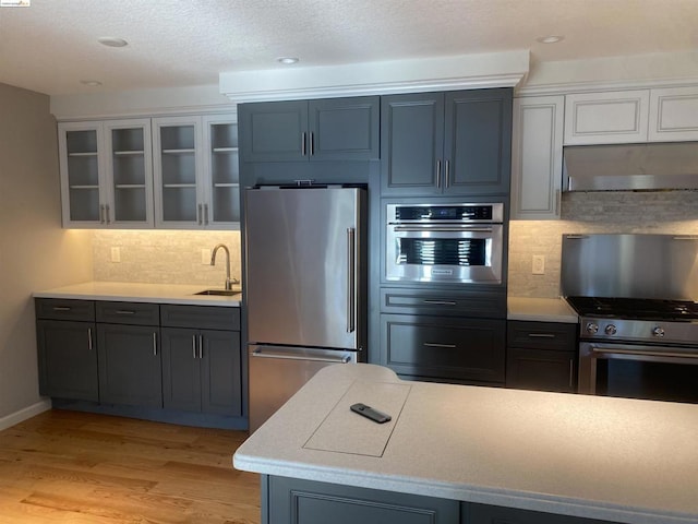 kitchen featuring white cabinetry, sink, light hardwood / wood-style floors, decorative backsplash, and appliances with stainless steel finishes